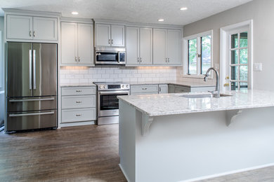 Inspiration for a large contemporary u-shaped dark wood floor and brown floor eat-in kitchen remodel in Atlanta with an island, an undermount sink, shaker cabinets, gray cabinets, marble countertops, white backsplash, subway tile backsplash and stainless steel appliances