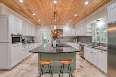 Example of a large eclectic u-shaped marble floor, beige floor and wood ceiling eat-in kitchen design with an undermount sink, recessed-panel cabinets, white cabinets, granite countertops, metal backsplash, stainless steel appliances, an island and black countertops