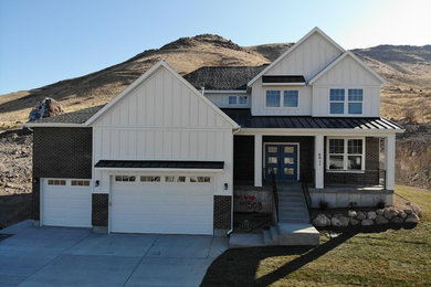 Example of a cottage white exterior home design in Salt Lake City with a mixed material roof
