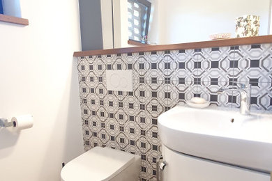 Kleine Landhaus Gästetoilette mit flächenbündigen Schrankfronten, weißen Schränken, Wandtoilette, grauen Fliesen, Keramikfliesen, grauer Wandfarbe, Travertin, Wandwaschbecken, beigem Boden und schwebendem Waschtisch in Hannover