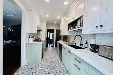 Example of a mid-sized trendy galley cement tile floor and white floor enclosed kitchen design in Toronto with an undermount sink, shaker cabinets, white cabinets, quartz countertops, white backsplash, ceramic backsplash, stainless steel appliances, no island and white countertops