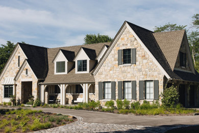 French country beige two-story stone house exterior photo in Chicago with a brown roof