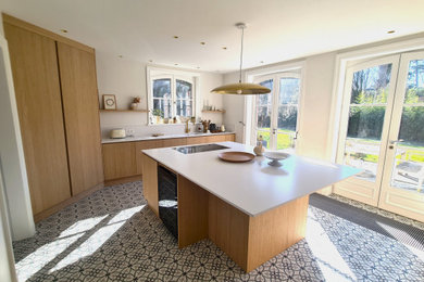 Idee per una grande cucina con lavello integrato, ante a filo, ante in legno chiaro, paraspruzzi bianco, pavimento in cementine e top bianco