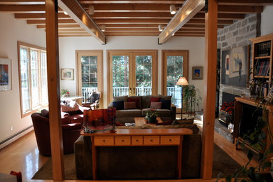 Large mountain style open concept medium tone wood floor living room photo in Other with white walls, a standard fireplace, a stone fireplace and no tv