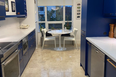 Example of a large trendy galley travertine floor and beige floor enclosed kitchen design in Toronto with an undermount sink, flat-panel cabinets, blue cabinets, quartz countertops, white backsplash, quartz backsplash, stainless steel appliances and white countertops