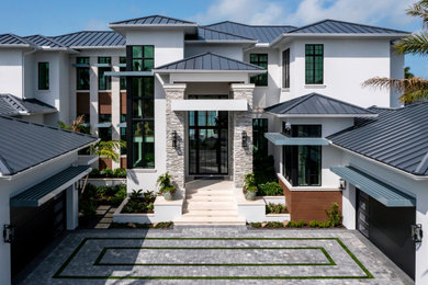 Inspiration for a huge modern white two-story stucco house exterior remodel in Miami with a metal roof and a black roof