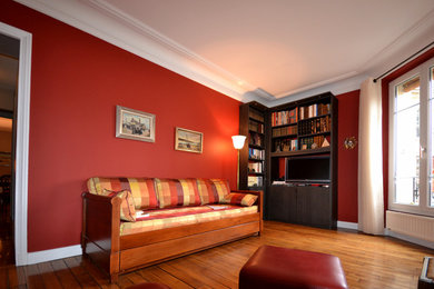 Mid-sized traditional enclosed living room in Paris with a library, red walls, dark hardwood floors, no fireplace and a freestanding tv.