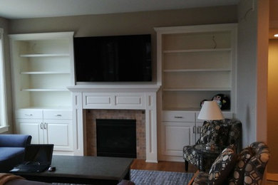 Foto de sala de estar tradicional con paredes grises, suelo de madera clara, todas las chimeneas, marco de chimenea de baldosas y/o azulejos, pared multimedia y suelo marrón