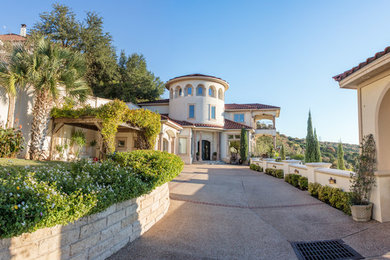 Example of a huge tuscan white two-story stucco house exterior design in Austin with a hip roof and a tile roof