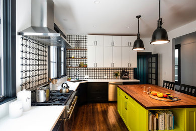 Photo of a mid-sized eclectic u-shaped separate kitchen in San Francisco with an undermount sink, recessed-panel cabinets, black cabinets, solid surface benchtops, multi-coloured splashback, ceramic splashback, stainless steel appliances, dark hardwood floors, with island, brown floor and white benchtop.