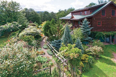 This is an example of a large rustic partial sun backyard gravel landscaping in New York.