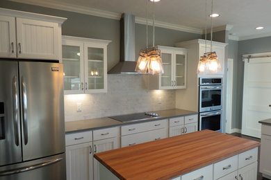 Enclosed kitchen - mid-sized craftsman u-shaped dark wood floor and brown floor enclosed kitchen idea in Other with shaker cabinets, white cabinets, solid surface countertops, white backsplash, stone tile backsplash, stainless steel appliances and an island