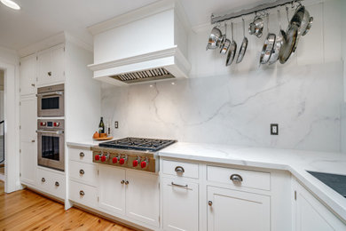 Inspiration for a small transitional galley medium tone wood floor and brown floor kitchen remodel in Other with an undermount sink, shaker cabinets, white cabinets, white backsplash and white countertops