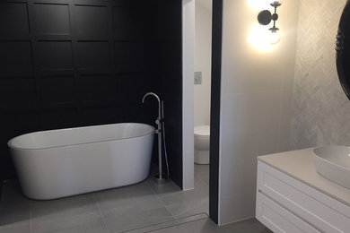 Cette image montre une grande salle de bain principale design avec un placard à porte shaker, des portes de placard blanches, une baignoire indépendante, WC à poser, un carrelage multicolore, des carreaux de céramique, un mur multicolore, carreaux de ciment au sol, une vasque, un plan de toilette en quartz modifié, un sol gris et un plan de toilette beige.