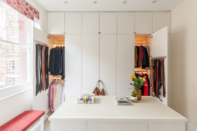 Inspiration for a contemporary gender-neutral walk-in wardrobe in London with white cabinets.