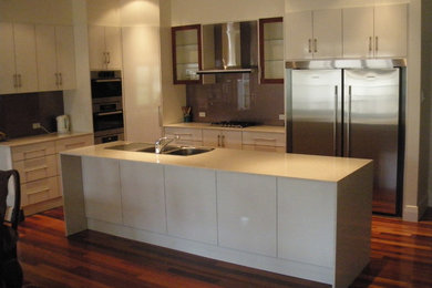 Inspiration for a large modern l-shaped eat-in kitchen in Adelaide with a double-bowl sink, flat-panel cabinets, white cabinets, quartz benchtops, brown splashback, glass sheet splashback, stainless steel appliances, dark hardwood floors and with island.