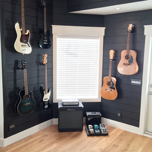 Medium sized rural walk-out basement in Calgary with black walls and medium hardwood flooring.
