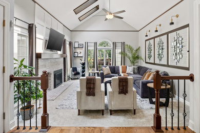 Inspiration for a mid-sized transitional open concept carpeted, beige floor, vaulted ceiling and wallpaper family room remodel in Philadelphia with beige walls, a standard fireplace, a brick fireplace and a wall-mounted tv