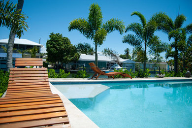 Pool - large coastal backyard concrete and l-shaped lap pool idea in Miami