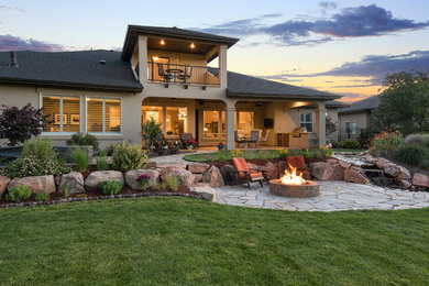 Large trendy beige two-story stucco house exterior photo in Boise with a hip roof and a shingle roof