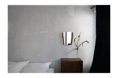 Cette photo montre une chambre parentale tendance de taille moyenne avec un mur gris, parquet foncé, une cheminée standard, un manteau de cheminée en pierre et un sol marron.