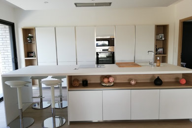 Inspiration for a large modern galley eat-in kitchen in Lille with an integrated sink, beaded inset cabinets, white cabinets, laminate benchtops, stainless steel appliances, ceramic floors, with island and white benchtop.