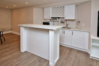 This is an example of a large look-out basement in Toronto with grey walls, laminate floors and brown floor.