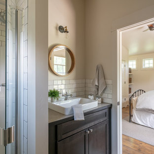 Example of a small transitional 3/4 white tile and subway tile medium tone wood floor and brown floor alcove shower design in Other with shaker cabinets, dark wood cabinets, beige walls, a vessel sink, laminate countertops, a hinged shower door and beige countertops