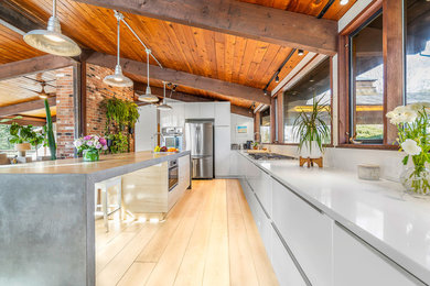 Example of a large minimalist u-shaped vinyl floor and brown floor eat-in kitchen design in New York with an undermount sink, flat-panel cabinets, white cabinets, quartz countertops, white backsplash, stone slab backsplash, stainless steel appliances, an island and white countertops