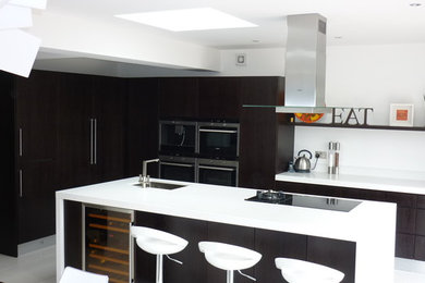 Inspiration for a large contemporary kitchen/diner in London with a single-bowl sink, flat-panel cabinets, dark wood cabinets, quartz worktops, stainless steel appliances, ceramic flooring, an island and white floors.