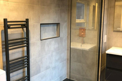 ロンドンにあるお手頃価格の小さなトランジショナルスタイルのおしゃれなバスルーム (浴槽なし) (黒いキャビネット、オープン型シャワー、一体型トイレ	、グレーのタイル、磁器タイル、グレーの壁、磁器タイルの床、一体型シンク、グレーの床、オープンシャワー、ニッチ、洗面台1つ、フローティング洗面台) の写真