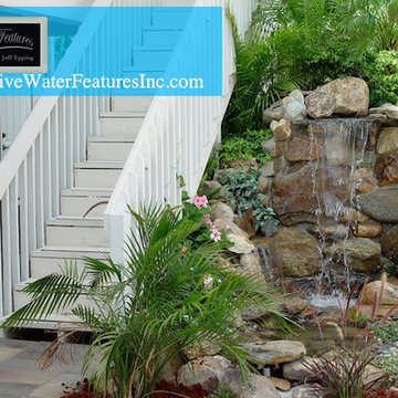 Tropical backyard room with pool waterfall, fireplace, and koi pond