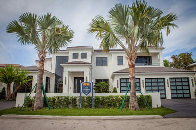 Photo of an expansive contemporary two-storey stucco white house exterior in Miami with a hip roof and a tile roof.