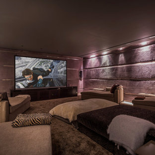 Cette image montre une grande salle de cinéma design fermée avec un mur violet et un téléviseur encastré.