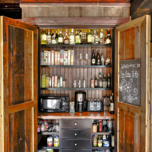 Exemple d'une arrière-cuisine parallèle montagne de taille moyenne avec un évier de ferme, un plan de travail en bois, un électroménager en acier inoxydable, un sol en bois foncé, un îlot central, un placard à porte shaker, des portes de placard rouges, une crédence marron, une crédence en bois et un sol marron.