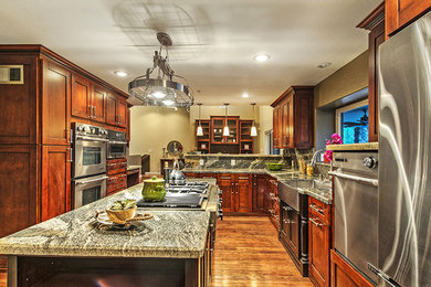 Eat-in kitchen - large traditional u-shaped medium tone wood floor eat-in kitchen idea in Phoenix with a farmhouse sink, shaker cabinets, medium tone wood cabinets, granite countertops, multicolored backsplash, stone slab backsplash, stainless steel appliances and an island