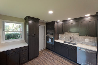 Example of a mid-sized classic u-shaped enclosed kitchen design in Cleveland with dark wood cabinets and quartz countertops