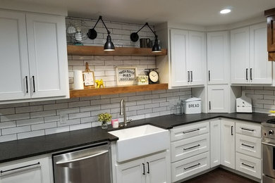 Inspiration for a large country u-shaped medium tone wood floor and brown floor enclosed kitchen remodel in Dallas with a farmhouse sink, shaker cabinets, white cabinets, granite countertops, white backsplash, ceramic backsplash, stainless steel appliances and no island