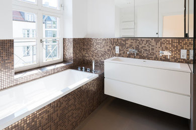 Photo of a mid-sized contemporary bathroom in Munich with an integrated sink, flat-panel cabinets, white cabinets, a drop-in tub, brown tile, mosaic tile and white walls.