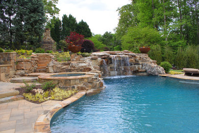 Inspiration for a large tropical backyard custom-shaped lap pool in Atlanta with a hot tub and natural stone pavers.