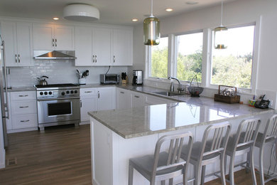 Large trendy u-shaped medium tone wood floor open concept kitchen photo in New York with recessed-panel cabinets, white cabinets, quartzite countertops, white backsplash, subway tile backsplash, stainless steel appliances, no island and a single-bowl sink