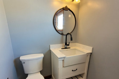 Inspiration for a small country medium tone wood floor and multicolored floor utility room remodel in Other with a farmhouse sink, flat-panel cabinets, white cabinets, quartz countertops, gray walls, a side-by-side washer/dryer and white countertops