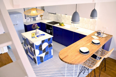 パリにある高級な中くらいなモダンスタイルのおしゃれなキッチン (ドロップインシンク、フラットパネル扉のキャビネット、青いキャビネット、珪岩カウンター、白いキッチンパネル、セラミックタイルのキッチンパネル、白い調理設備、磁器タイルの床、青い床、白いキッチンカウンター、板張り天井) の写真