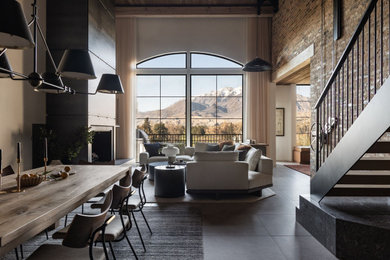 Example of a large urban loft-style slate floor, black floor, exposed beam and brick wall living room design in Salt Lake City