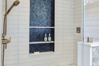 This is an example of a large bohemian ensuite bathroom in New York with flat-panel cabinets, blue cabinets, an alcove shower, a bidet, grey tiles, porcelain tiles, grey walls, porcelain flooring, marble worktops, grey floors, a hinged door, white worktops, a shower bench, double sinks, a freestanding vanity unit and a vaulted ceiling.
