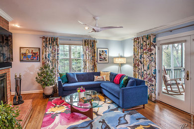 Inspiration for a mid-sized contemporary open concept medium tone wood floor living room remodel in Baltimore with blue walls, a standard fireplace, a brick fireplace and a wall-mounted tv