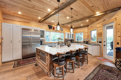 Photo of a country l-shaped kitchen in Birmingham with beaded inset cabinets, white cabinets, stainless steel appliances, medium hardwood floors, brown floor and black benchtop.