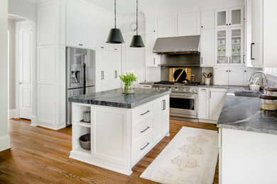 Inspiration for a mid-sized transitional l-shaped medium tone wood floor and brown floor eat-in kitchen remodel in Charlotte with an undermount sink, shaker cabinets, white cabinets, quartzite countertops, gray backsplash, porcelain backsplash, stainless steel appliances, an island and black countertops