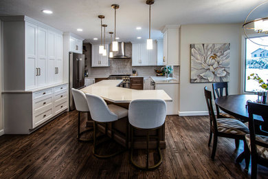 Large transitional u-shaped medium tone wood floor and brown floor kitchen photo in Cleveland with an undermount sink, raised-panel cabinets, white cabinets, quartz countertops, white backsplash, ceramic backsplash, stainless steel appliances and beige countertops