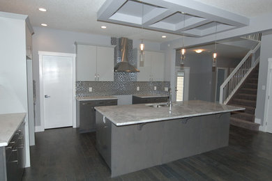 Photo of a mid-sized contemporary l-shaped kitchen in Edmonton with an undermount sink, shaker cabinets, grey cabinets, grey splashback, mosaic tile splashback, stainless steel appliances, dark hardwood floors and with island.
